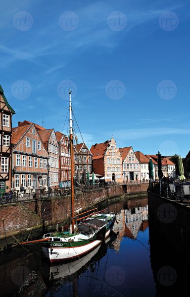 Stade, Hansehafen, Historische Gebäude entlang eines ruhigen Kanals mit einem Boot im Vordergrund.